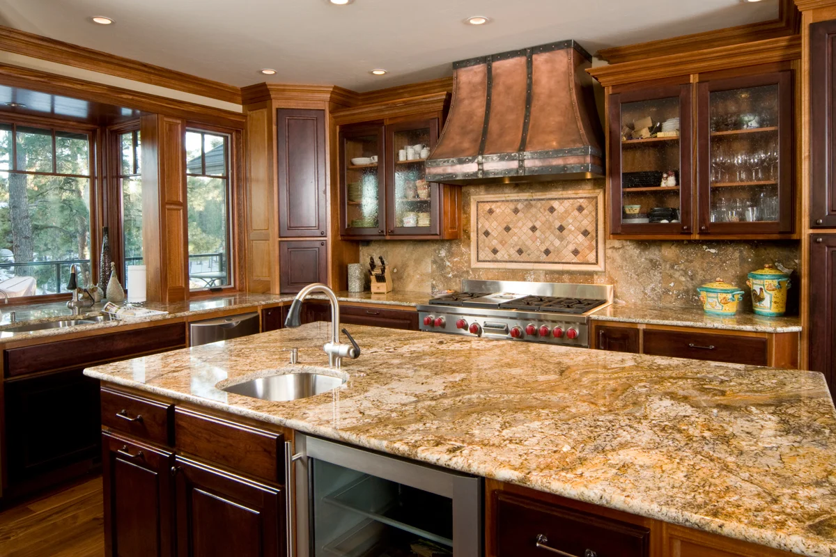 Kitchen with white cabinetry, a stone island and pendant lighting